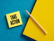 The word take action on yellow sticky note paper with a pencil and binder.