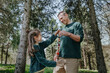 © Westend61 - Smiling father and daughter holding natural necklace standing near trees in forest