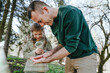 © Westend61 - Happy girl examining bug on father's hand with magnifying glass in forest