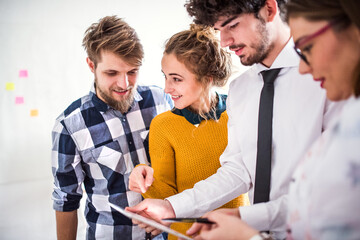 Young group of colleagues working on a new project together in a startup company office. Working in co-working space.