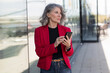 © Westend61 - Businesswoman holding smart phone standing at street