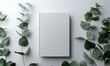 © Lucky Ai - empty blank white book cover mock up and green eucalyptus branch on white table background