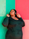 Fototapeta  - Mujer con sobrepeso disfrutando de música en fondo bicolor