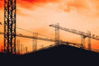 Construction site building scaffold and cranes in silhouette