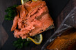 Hot smoked trout fillet served on the black board with lemon and parsley and a vacuum packed piece