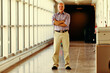 Senior man reflects, standing in bright corridor