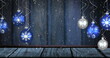 Image of mountain over snow and baubles on wooden background