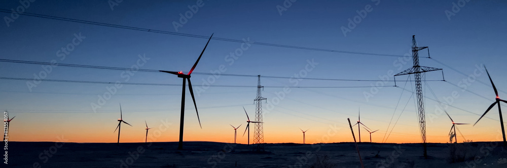 Sustainable energy concept with silhouette of wind turbines at sunset in a snowy landscape, ideal for environmental awareness campaigns and Earth Day promotions