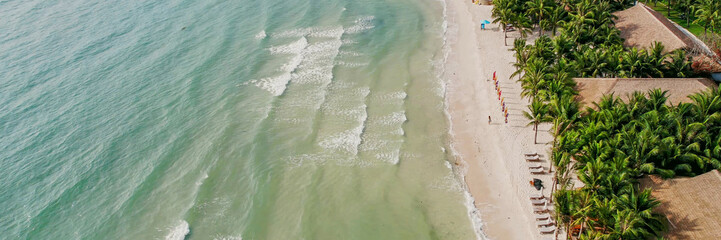 Wall Mural - Serene aerial view of gentle sea waves washing over a sandy beach, ideal for travel themes and summer vacation backgrounds