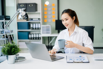 Asian businesswoman working with working notepad, tablet and laptop documents talking on the smartphone, tablet and laptop video call tax