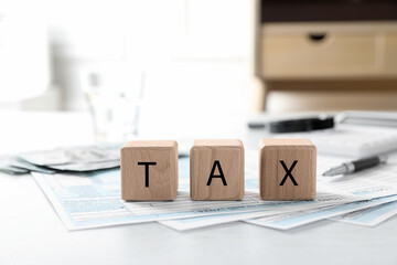 Wall Mural - Wooden cubes with word Tax and documents on light table, closeup. Space for text