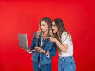 Excited impressed two women holding work use laptop point index finger notebook screen. Recommend, advice, reading happy news. Incredible omg screaming girl wearing denim jean concept image.