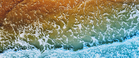 Wall Mural - Ocean surf. Waves roll onto the shore. View from above. Nature abstract background. Horizontal banner