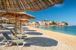 An empty beach with sun umbrellas and vacant sunbeds on the Primosten beach, Croatia