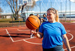 Portrait of young woman on basketball court holding ball in her hands.