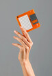 Crop female hand holding orange floppy disk in studio