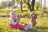 Fototapeta  - little girl with her dachshund dog in the summer garden