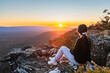 Young woman sitting on edge of Reed Lookout cliff while enjoying sunset in Grampians mountains, Victoria, Australia