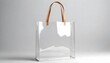 © Sema - A clear shopping bag with a sturdy leather handle hanging against a white background