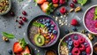 Assorted smoothie bowls decorated with fresh fruits, nuts, and seeds on a textured background