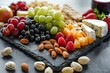 This vibrant image showcases a variety of fresh fruits and cheeses, arranged on a dark slate board for a visually appealing snack