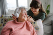 Cute girl putting headphones on gradmother head. Portrait of an elderly woman spending time with granddaughter.