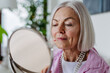 Skincare for mature woman. Portrait of beautiful older woman with gray hair putting makeup on.