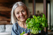 Portrait of beautiful mature woman taking care of plants on balcony. Spending free weekend at home.