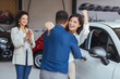 Happy couple buying a car at the dealership and holding the keys. Family celebrating buying a car at a car dealership. Happy couple hugging after buying a car at the dealership