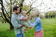New parents holding small toddler, baby, outdoors in spring nature. Older First-time parents.