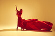 © master1305 - Passion in motion. Beautiful woman, dancer in flowing elegant red dress making powerful performance against sand color background. Concept of art, classical dance, beauty and fashion, aesthetics