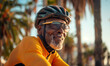 © Sophie  - Happy senior black man cycling on vacation. Smiling elderly african american pensioner exercising outdoors on pedal bike. Bicycle safety helmet & sun protection Palm trees