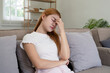 © Natee Meepian - Woman asian frustrated ill sit sofa suffer headache migraine pain have health problem in house living room