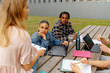 Group of students paying attention to a classmate while she gives an explanation and exposes her opinions about a class project. Multiracial group of students on campus.