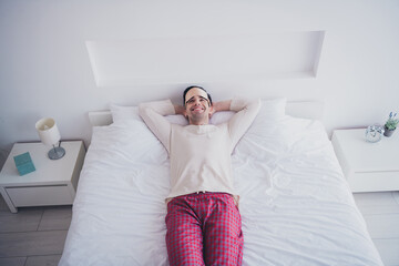 Poster - Photo of attractive young man hands hold behind head lying in soft comfy bed white room interior inside