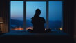 © realone952 - A girl sits on her bed at night suffering from insomnia. Silhouette of a girl at home at night looking out the window next to the lamp