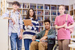 Portrait of diverse group of teenage students looking at camera in school library and smiling