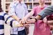 © Seventyfour - Close up of multiethnic group of students stacking hands in school library and huddling in unity copy space