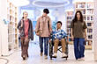 © Seventyfour - Full length portrait of inclusive group of teenagers walking towards camera in school library