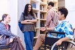 © Seventyfour - Side view portrait of cheerful Middle Eastern boy with disability talking to group of friends in school lounge