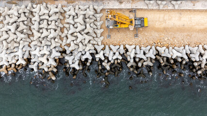 Aerial view of breakwater construction. Crane puts tetrapods on breakwater construction