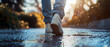 © bagotaj - A young man walking on the wet asphalt of a street. Sunset, late afternoon sunlight. Ground level viewpoint. Legs and shoes are visible.