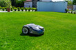 robot mower working in the garden on beautiful green grass