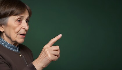 Wall Mural - An elderly woman pointing his finger against a dark green background