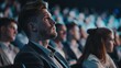 © Антон Сальников - A young man waiting for his presentation as he sits in a crowded business conference. He is watching an inspirational presentation about entrepreneurship and financial opportunities for a corporate