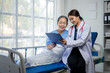 © apichat - A woman doctor is talking to a patient in a hospital bed