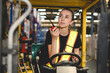 © bigy9950 - warehouse, radio, and forklift in shipping warehouse. Female transport worker in safety uniform transport worker talking on walkie talkie, drives forklift at freight cargo warehouse port.