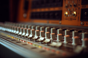 Retro audio mixing console with faders and knobs in warm colors conveys a sense of nostalgia and professionalism for audio engineers and music producers.