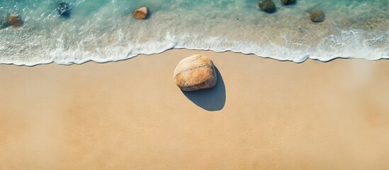 Poster - Top view of a stone resting on the sandy beach creating a serene summer beach background with ample copy space for images