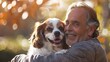 A cheerful middle aged man is sitting down affectionately cuddling his female Cavalier King Charles Spaniel perched on his lap This scene embodies the idea of animals as best companions and